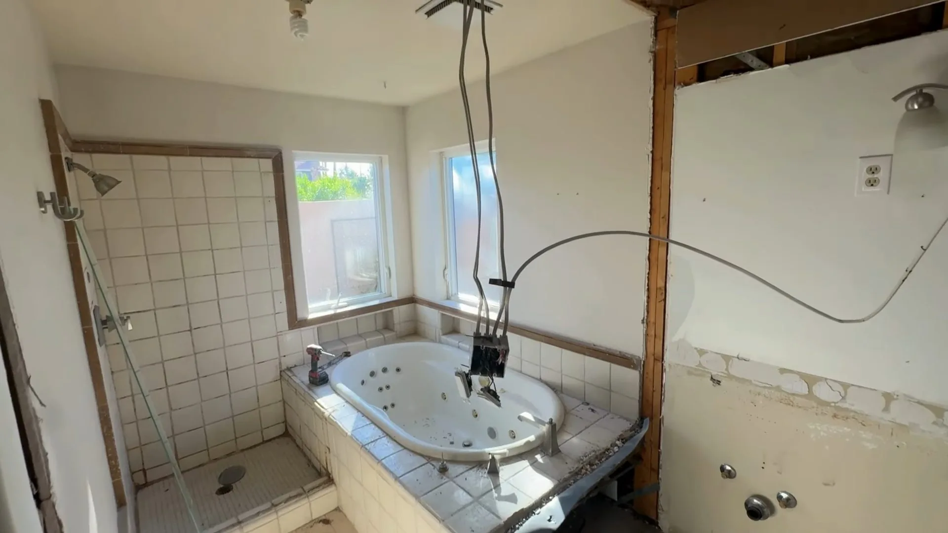 Bathroom with a tiled whirlpool tub, a walk-in shower and wall sections opened for work