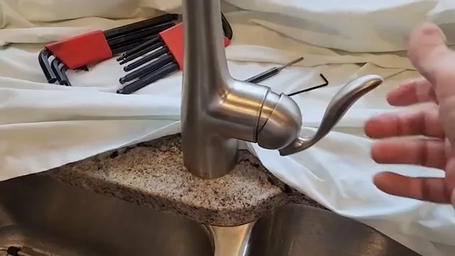 Brushed nickel single-handle faucet on a granite counter with a set of hex keys laid out on a cloth
